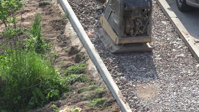 close up of asphalt worker in construction site with manual compactor plate. 4K UHD video clip. 
