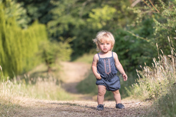 Baby girl with blue jeans costume standing on path