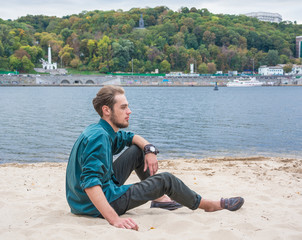 Young man is sitting near a river