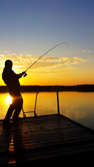 Fototapeta na wymiar Young man fishing on a lake at sunset