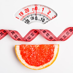 Grapefruit with measuring tape on weight scale. Dieting