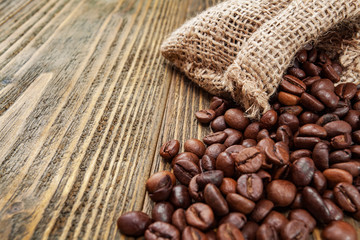 Coffee beans in sackcloth bag on wooden table. Close up. Selective focus