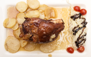 pork shank with potatoes cooked in the oven and tomatoes
