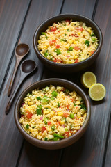 Vegetarian couscous salad made with bell pepper, tomato, cucumber, red onion and sweet corn kernels, photographed with natural light (Selective Focus, Focus in the middle of the first salad)