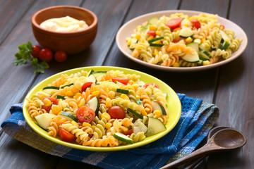 Vegetarian pasta salad made of tricolor fusilli, sweet corn, cucumber and cherry tomato, photographed with natural light (Selective Focus, Focus one third into first salad)