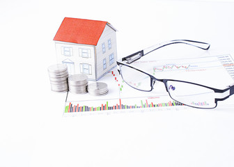 Mortgage loans concept with paper house and coins stack with eyeglasses on financial report