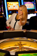 Young blond woman playing roulette in casino and winning