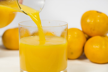 Filling a glass of natural tangerine orange juice