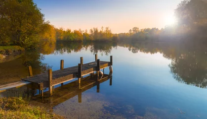 Foto auf Acrylglas See / Teich Holzsteg auf einem ruhigen See bei Sonnenuntergang