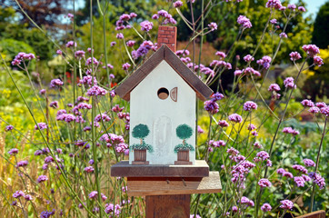 Fototapeta na wymiar Little white birdhouse in spring garden