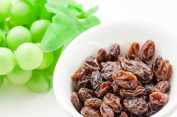 Raisins in white bowl and green grapes.