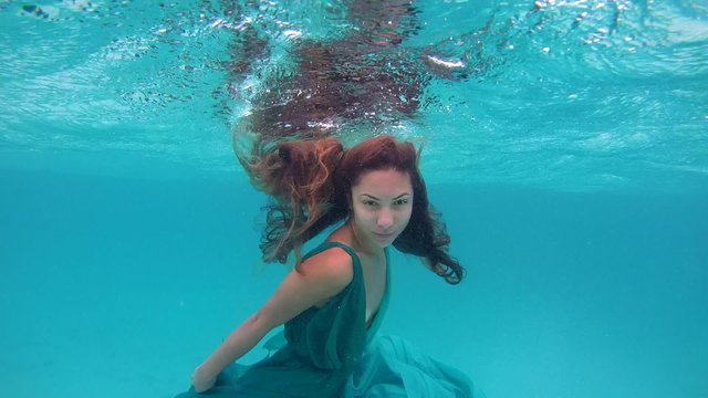 UNDERWATER: Young beautiful girl in dress posing submerged under water, Indian Ocean, Maldives
