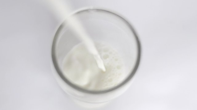 Glass of milk. Fill a glass of milk. Overhead view.