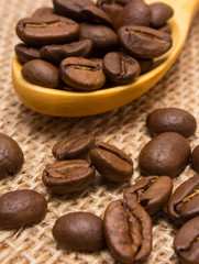 Heap of coffee beans with wooden spoon on jute canvas