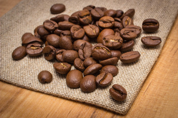 Heap of coffee beans on jute burlap on table
