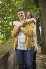 Young coule in 20s, girlfriend hugging boyfriend.