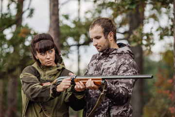 Instructor with woman hunter aiming rifle at firing nature