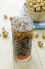 Cola with Ice and Popcorn on a wooden background