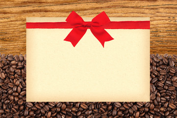 Postcard with red bow on roasted coffee beans and wooden backgro