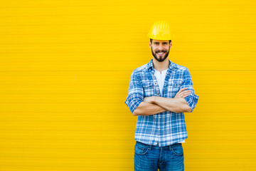 adult worker with helmet on yellow wall - obrazy, fototapety, plakaty