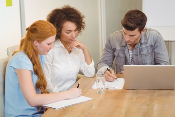 Fototapeta premium Colleagues writing on documents as businesswoman looking at them