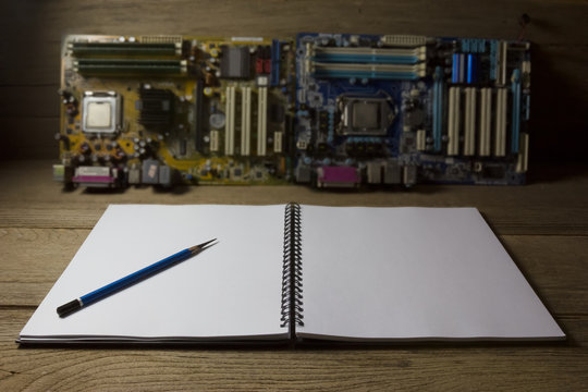 notebook with motherboard on wood background