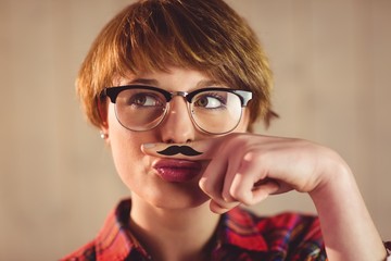 Pretty young woman with mustache on finger