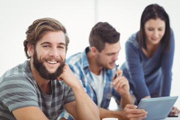 Portrait of smiling man with coworkers using digital tablet 
