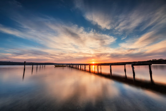 Lake sunset. Magnificent long exposure lake sunset with boat and a wooden pier