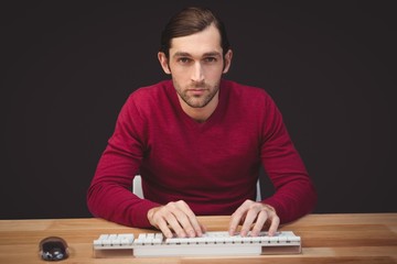 Portrait of serious man typing on keyboard at desk