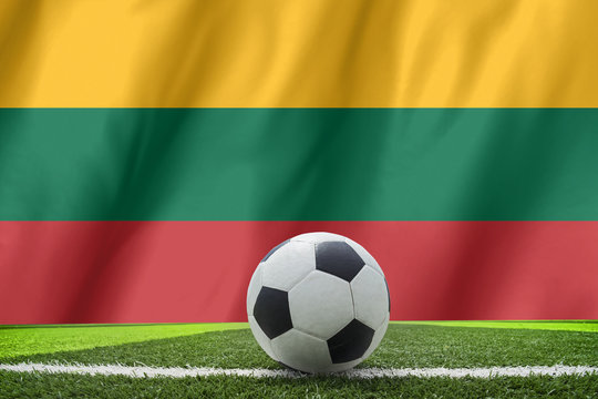 Soccer ball and national flag of Lithuania lies on the green gra