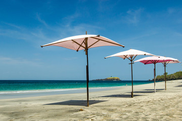 Fototapeta na wymiar pink umbrella on a tropical beach with a beautiful ocean view