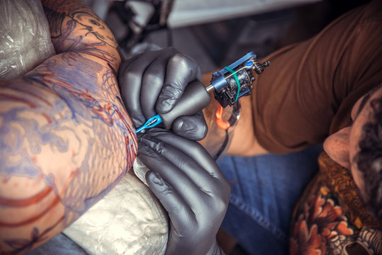Professional tattooist at work in tattoo parlor