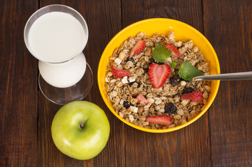 muesli with strawberries and a glass of milk on wooden background
