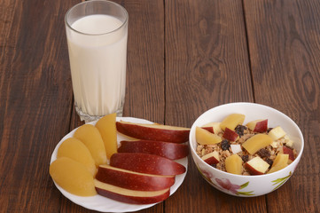 muesli with peach, apple and a glass of milk on wooden background
