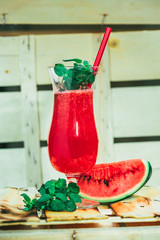 watermelon smoothie and fresh on a light wood background with red straw. selective focus to mint