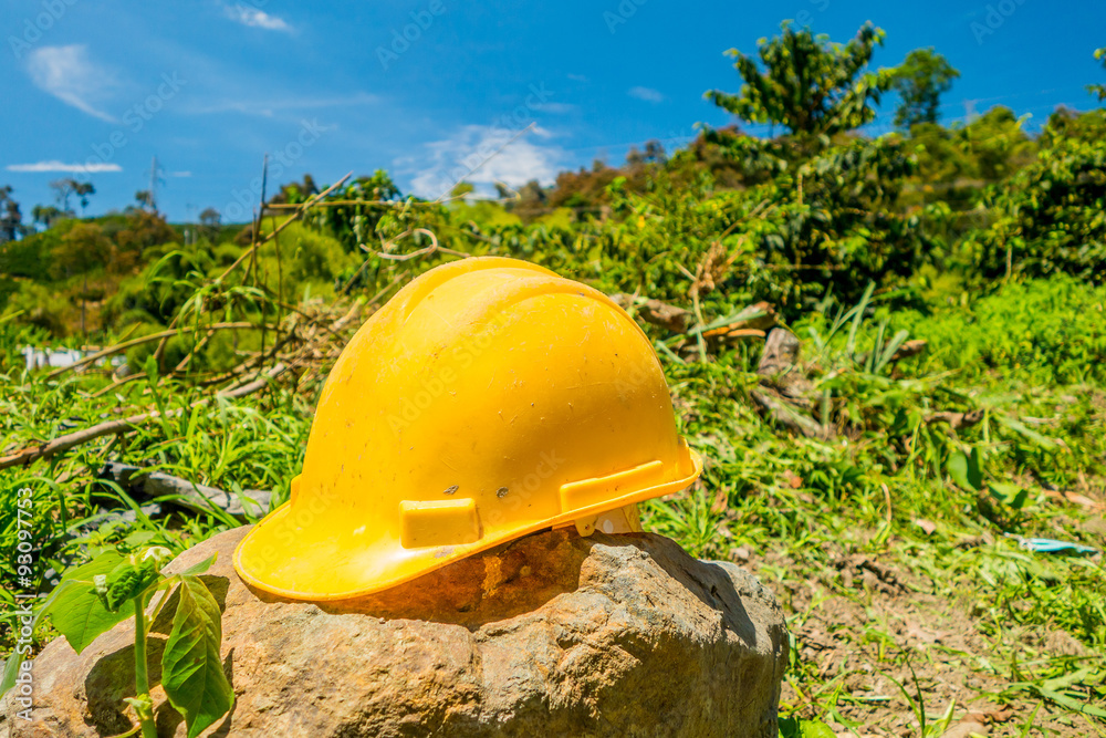 Wall mural yellow hard hat with a coffee plantation farm in the background