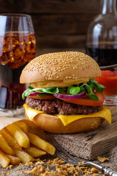 Delicious burger with chips and soda on wooden table.
