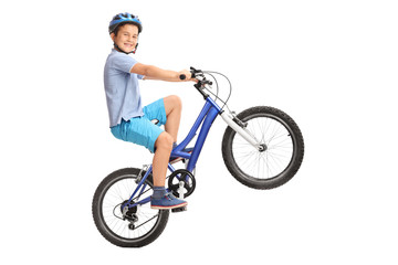 Joyful little boy performing a wheelie with his bike