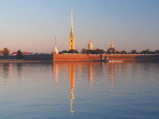 Key view of the Peter and Paul fortress across the Neva River reflected in quiet water at sunrise morning. The original citadel of Saint Petersburg, Russia, founded by Peter the Great in 18th century