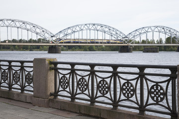 Naklejka premium Railway Bridge with Train and Banks of River Daugava, Riga