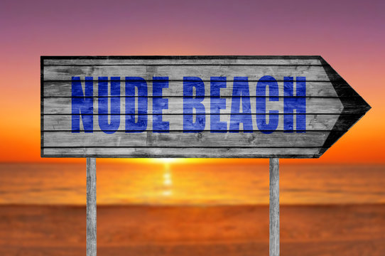 Nude Beach wooden sign with on a beach background