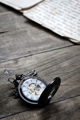 Old vintage pocket watch lying on wooden background