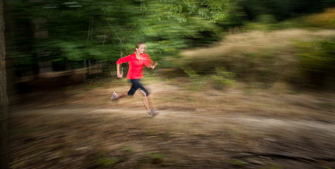 Young woman running outdoors in a forest, going fast