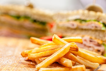 french fries with club sandwich on wooden background