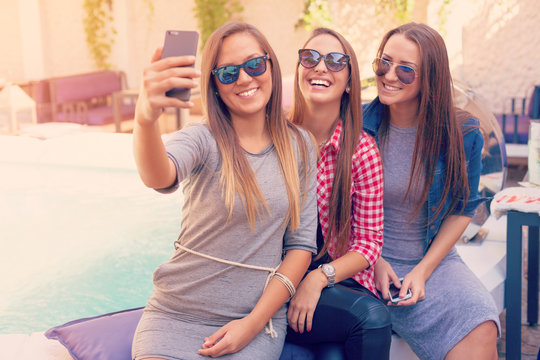 Young three girls laughing and taking selfie