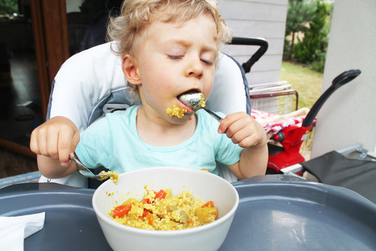 two years old baby boy eating dinner outside house