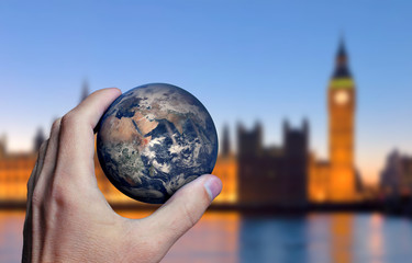 Earth planet in male hand. London city background. Elements of this image furnished by NASA