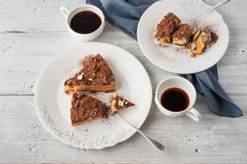 Two plate with coffee mousse and cups of coffee on the white wooden table