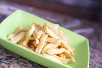 Potatoes fries in green plate on kitchen table